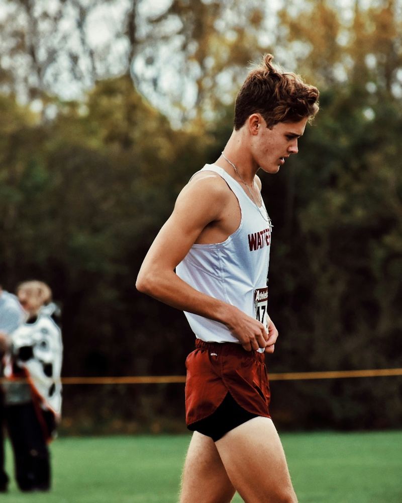 A cross country runner in a team singlet before the start