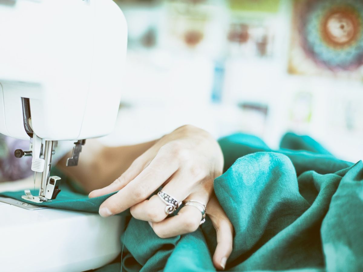 Hands guiding fabric through a sewing machine
