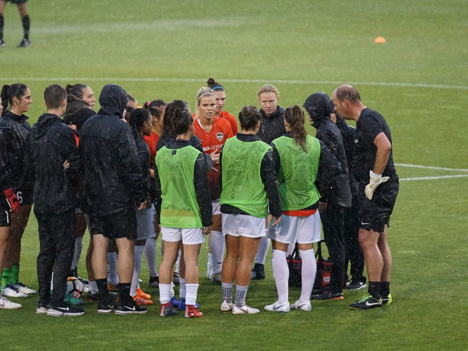 A club soccer team huddled on the field in training bibs